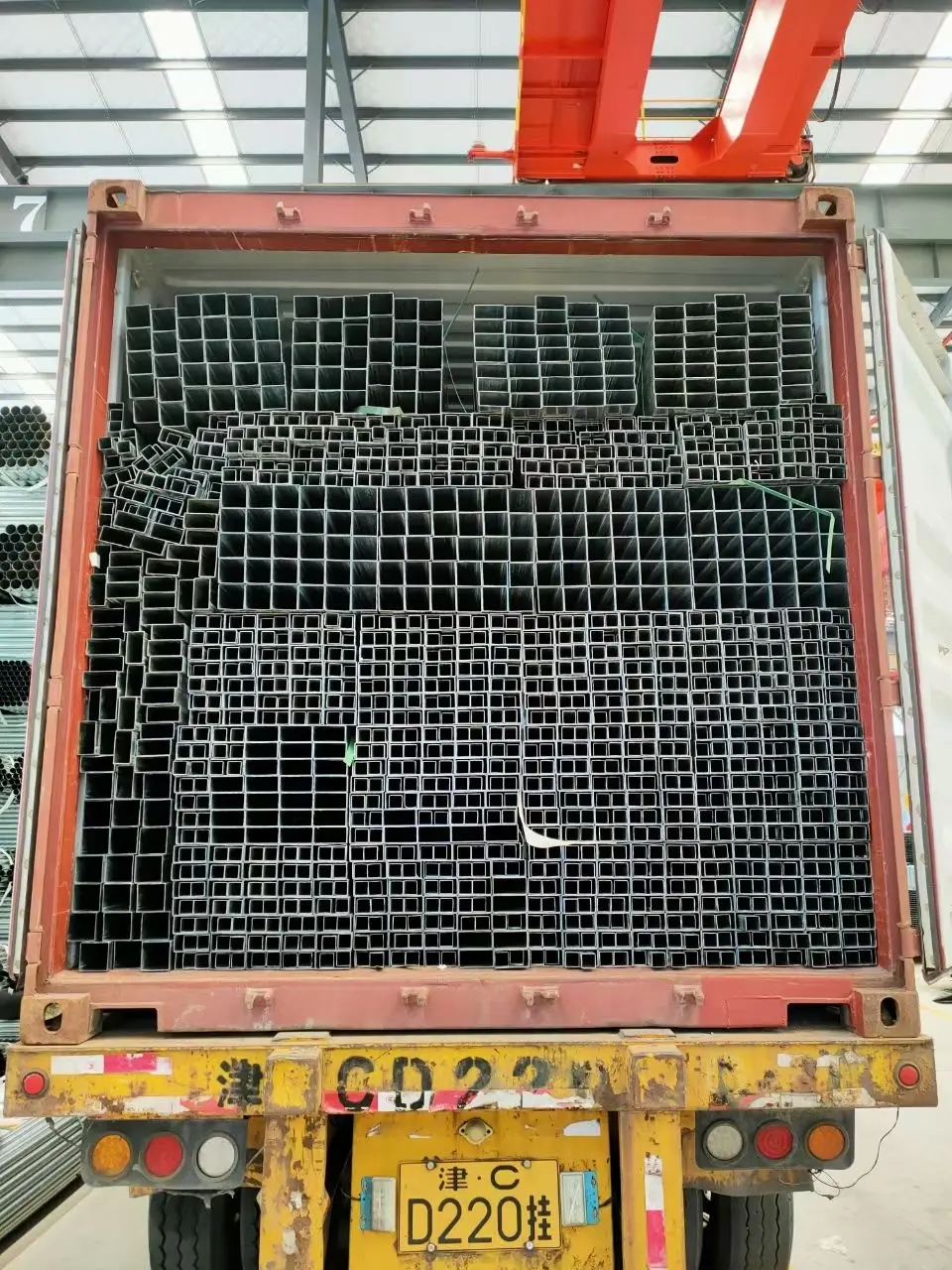 Bundled square steel tubes being loaded into export containers