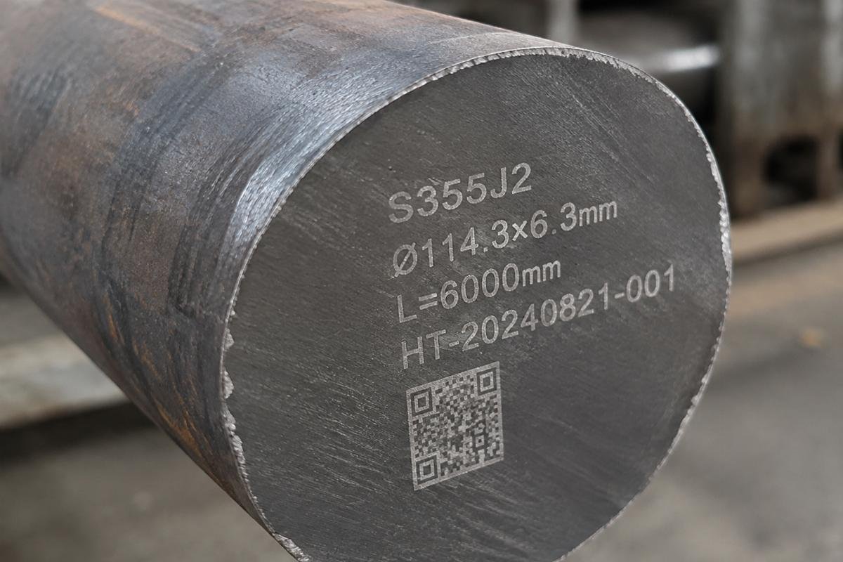 Close-up view of laser-marked traceability codes on a custom-cut S355J2 steel tube end